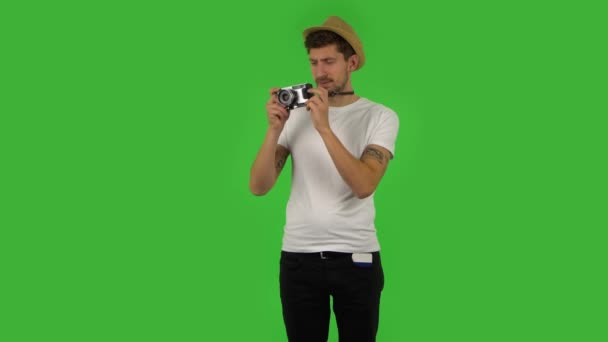 Turista en sombrero de vacaciones toma fotos en una cámara retro. Pantalla verde — Vídeos de Stock