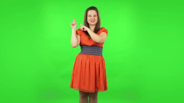 コピースペースのある何かのための指を指すかわいい女の子。緑の画面 — ストック動画