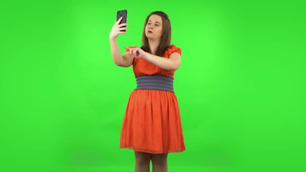 Linda chica haciendo selfie en el teléfono móvil y luego buscando fotos. Pantalla verde — Vídeos de Stock