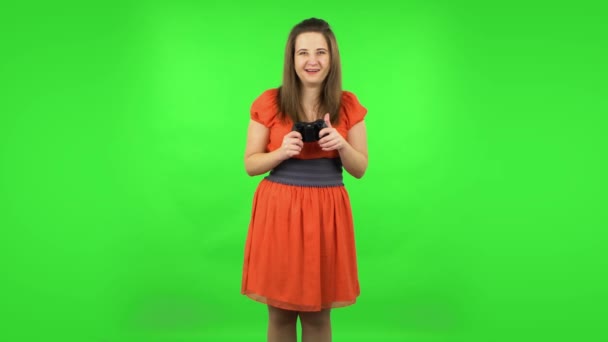 Cute girl playing a video game using a wireless controller with joy and rejoicing in victory. Green screen — Stock Video