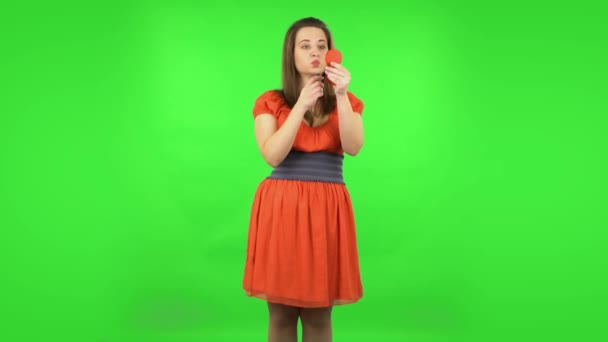 Cute girl is painting her lips looking in red mirror. Green screen — Stock Video