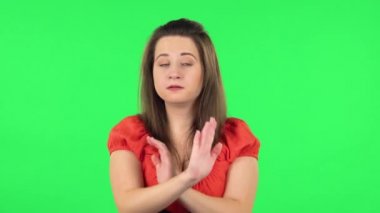 Portrait of cute girl strictly gesturing with hands crossed making X shape meaning denial saying NO. Green screen