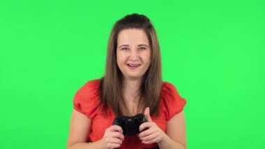 Portrait of cute girl playing a video game using a wireless controller with joy and rejoicing in victory. Green screen