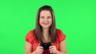 Portrait of cute girl playing a video game using a wireless controller with joy and rejoicing in victory. Green screen