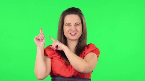 Porträt eines süßen Mädchens, das mit dem Finger auf etwas mit Kopierraum zeigt. Grüner Bildschirm — Stockvideo
