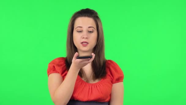 Портрет милой девушки, которая просит информацию в сети по телефону. Зеленый экран — стоковое видео