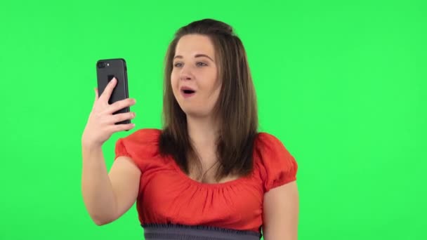 Портрет милой девушки, говорящей для видео чата с помощью мобильного телефона и радоваться. Зеленый экран — стоковое видео
