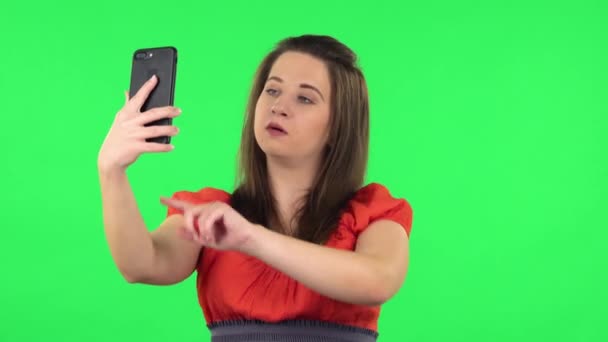Portrait of cute girl making selfie on mobile phone then looking photos. Green screen — Stockvideo