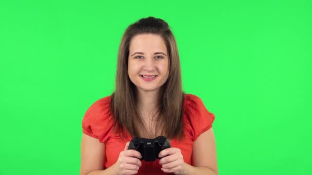 Портрет милой девушки, играющей в видеоигру с помощью беспроводного контроллера с радостью и радостью в победе. Зеленый экран — стоковое видео