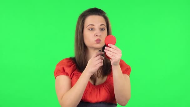 Portrait of cute girl is painting her lips looking in red mirror. Green screen — 图库视频影像