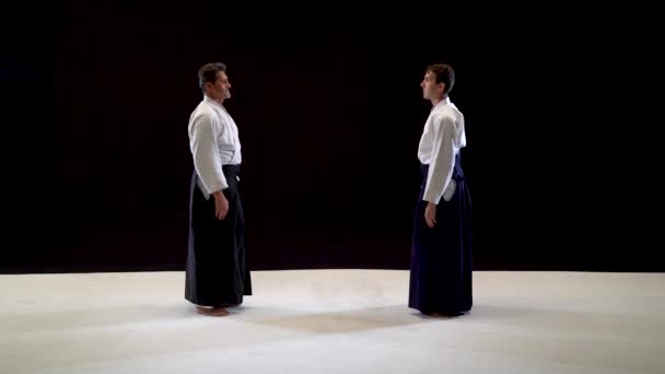 Twee meesters vechtsport Aikido buigen voor elkaar. Geïsoleerd op zwart-wit achtergrond. — Stockvideo