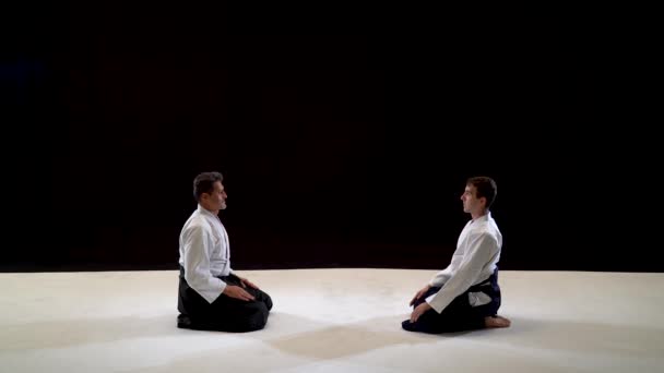 Twee meesters vechtsport Aikido buigen voor elkaar. Geïsoleerd op zwart-wit achtergrond. — Stockvideo
