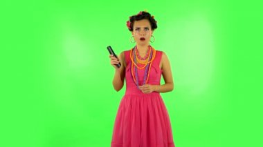 Woman with TV remote in her hand, switching on TV bored and is very scared. Green screen