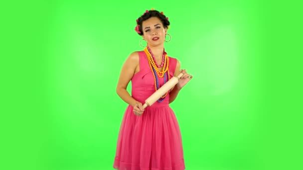 Girl with a rolling pin in her hands seductively looks at the camera. Green screen — Stockvideo