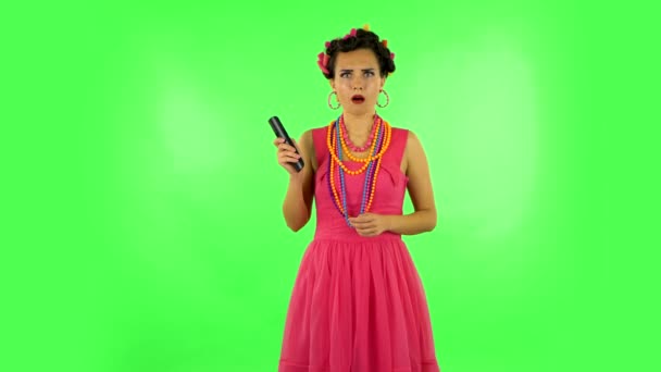 Woman with TV remote in her hand, switching on TV bored and is very scared. Green screen — Stock Video