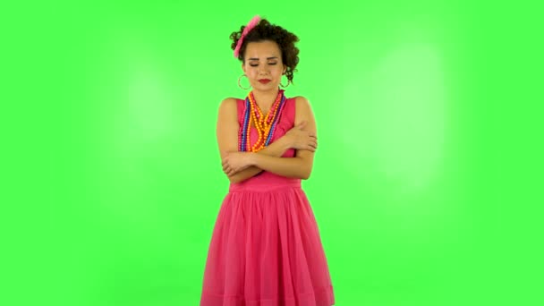 Lovely girl gently strokes her shoulders, smiles, and looks coquettishly at the camera on green screen at studio. — Stok video