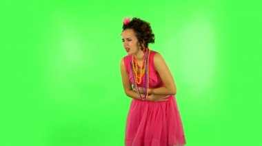 Cute female feels very bad, her stomach hurts against green screen at studio.