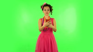 Genç bir kadın cep telefonuyla selfie çekiyor sonra da yeşil ekrana bakıyor.