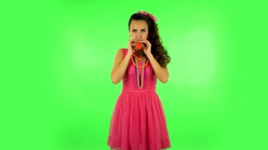 Curly girl inflates a bright red ball then rejoicing. Green screen