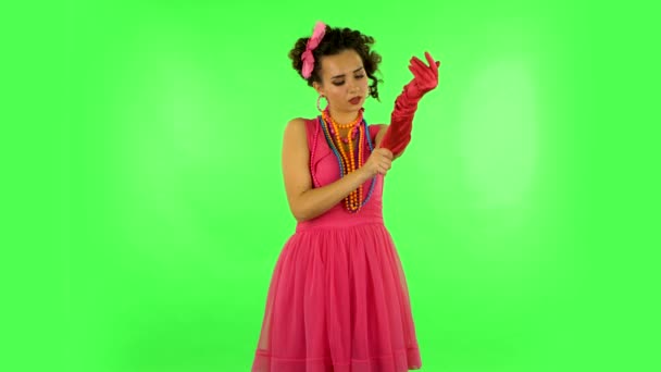 Attractive girl puts on her gloves and throws nearby on green screen — Stok video