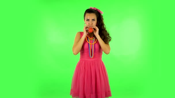 Curly girl inflates a bright red ball then rejoicing. Green screen — Wideo stockowe