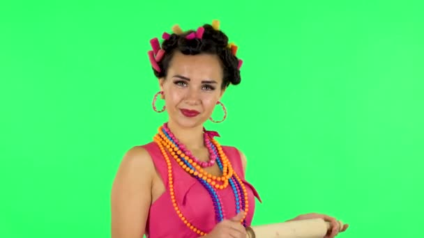 Girl with a rolling pin in her hands seductively looks at the camera. Green screen — Stock videók