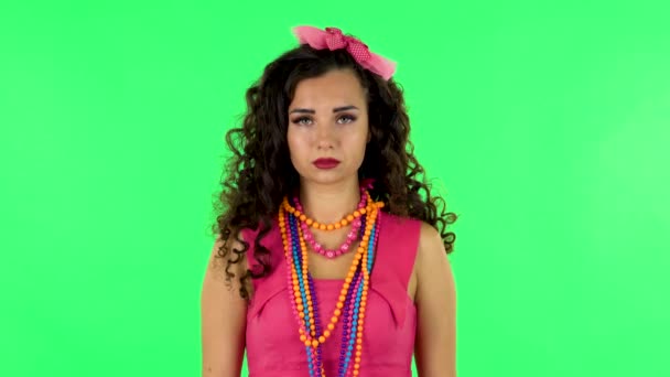 Νεαρή γυναίκα στέκεται, απλώνεται με χαμόγελο και κοιτάζει την κάμερα. Πράσινη οθόνη — Αρχείο Βίντεο