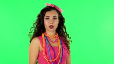 Cute girl smiles and blowing kiss then showing heart with fingers at studio. Green screen