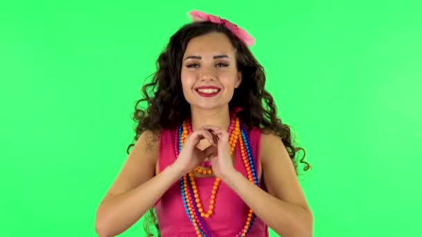 Cute girl smiles and showing heart with fingers then blowing kiss at studio. Green screen — Stock videók