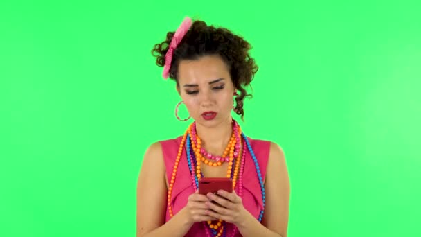 Young woman texting on her phone on green screen — Stockvideo