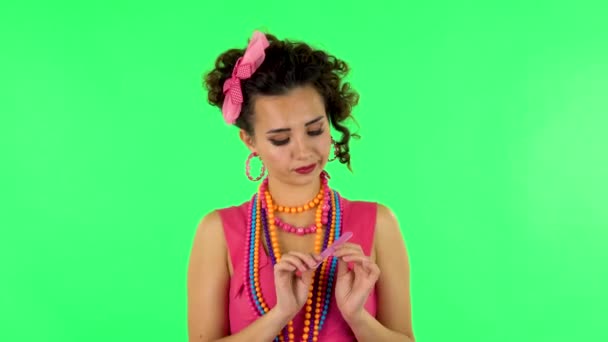 Girl makes herself manicure with pink nail file on green screen at studio — Stok video