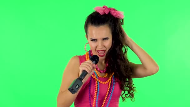 Ελκυστική κοπέλα τραγουδά σε ένα μικρόφωνο και κινείται στο ρυθμό της μουσικής. Πράσινη οθόνη — Αρχείο Βίντεο