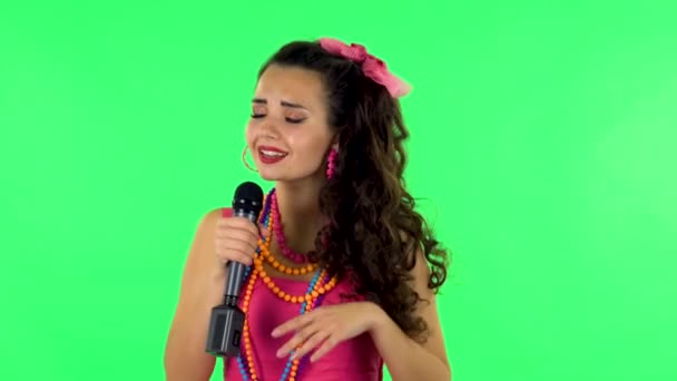 Девушка поёт в микрофон и переходит к ритму музыки. Зеленый экран — стоковое видео
