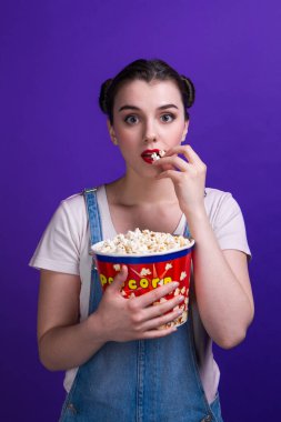 Mor arka planda lezzetli patlamış mısırı olan genç bir kadın.