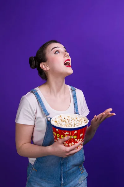 Wow mujer mirando hacia arriba y lanzando palomitas de maíz sobre fondo azul —  Fotos de Stock