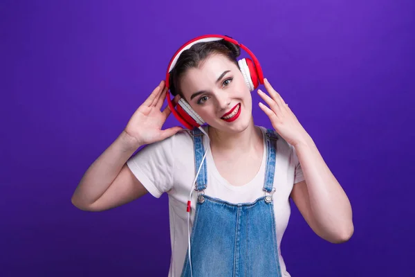 スタジオで青の背景に隔離された大きな赤いヘッドフォンの幸福の女性の肖像. — ストック写真