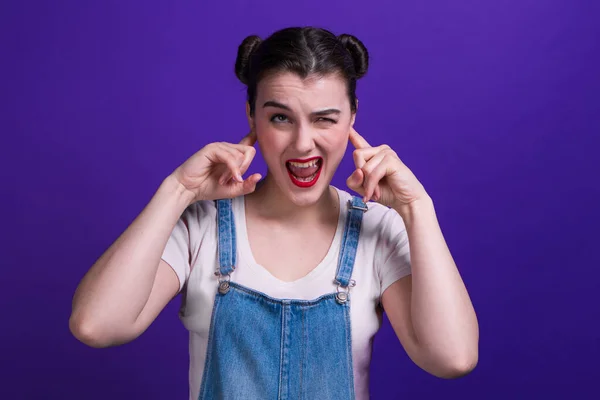 Mladá dívka zakrývající si uši rukama, na purpurovém pozadí — Stock fotografie