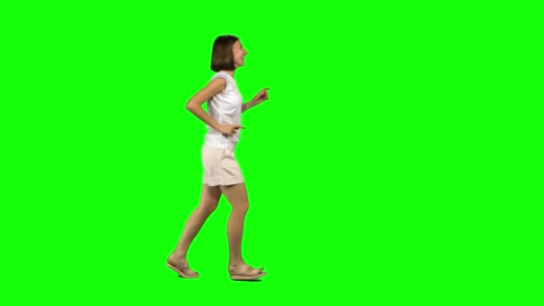 갈색 머리에 곱슬곱슬 한 머리를 한 젊은 여자가 초록색 화면에 미소를 띠고 달리고 있습니다. 크로마 키 , 4k 샷. 프로필 뷰 — 비디오