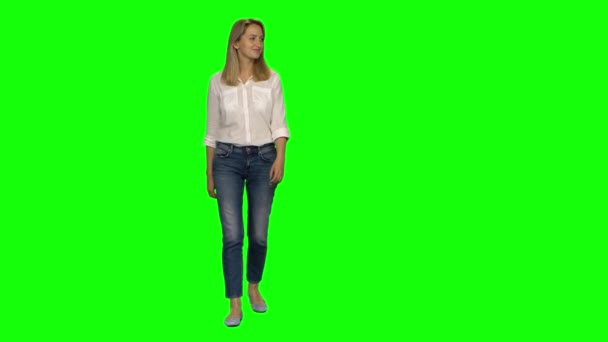 Blond kvinna är lugnt promenader och ler på grön skärm. Chroma nyckel, 4k skott. Framifrån. — Stockvideo