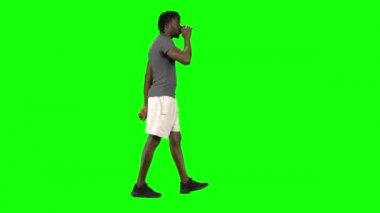 Yeşil Ekran, Chroma Key 'de yürüyen ve kahve içen Afrikalı Amerikalı bir adam. Profil görünümü.