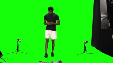 Sahne arkasında Afro-Amerikan bir adam yürüyor ve mesajlaşıyor. Cep telefonuyla Green Screen 'e gidiyor. Ön görünüm.