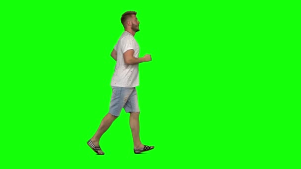 Бородатый парень спокойно бегает на зеленом фоне экрана. Chroma key, 4k shot. Профиль . — стоковое видео