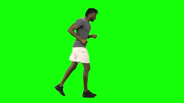 アフリカ系アメリカ人の男がグリーンスクリーンで走ってるクロマ・キー。プロフィールビュー. — ストック動画