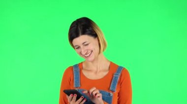 Genç, gülümseyen bir kadın telefonunda mesaj atıyor. Yeşil Ekran