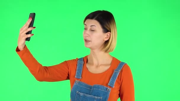 Дівчина розмовляє для відео чату за допомогою мобільного телефону. Зелений екран — стокове відео