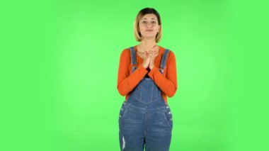 Girl looks with tenderness with folded arms in front of her. Green screen