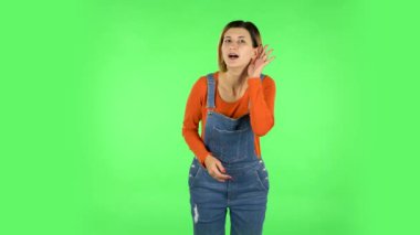 Woman holding hand near ear trying to listen to interesting news expressing communication concept. Green screen