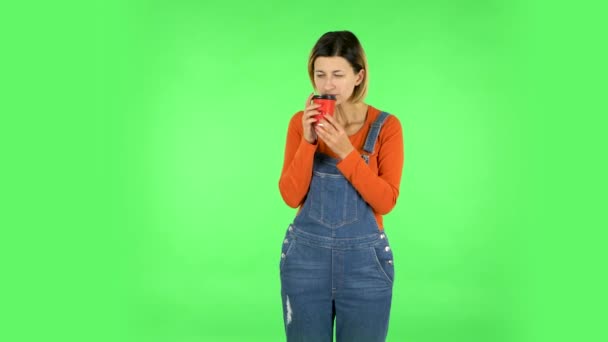 Девушка пьет неприятный кофе и отвратительно на зеленом экране — стоковое видео