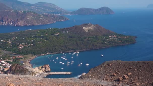 Vista desde la isla Vulcano en las Islas Lipari en el mar Mediterráneo. Edificios, árboles verdes y cielo azul. Yates de vela y otros buques. Sicilia, Italia — Vídeos de Stock