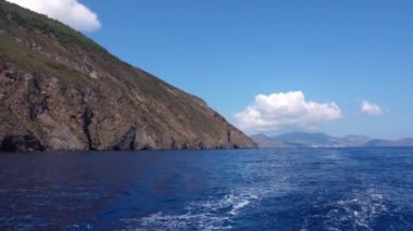 Lipari Adaları 'ndaki Akdeniz' de yeşil ağaçlar ve binalarla yüzen yat manzarası. Dağlar ve mavi gökyüzü. Sicilya, İtalya